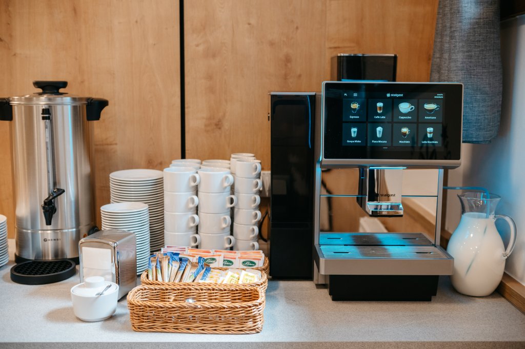 Zdjęcie przedstawia jadalnię, po prawej stronie automat do kawy, na wprost filiżanki cukier herbata, kawa po lewej stronie warnik z gorącą wodą.